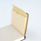 A close-up of cream pocket notebook folder open and adhered to a planner on white background