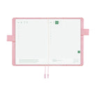 An open pink planner with white grid pages, ribbon bookmarks, and side loops, photographed on a clean white background.