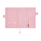 Pink interior of a Hobonichi Techo cover laid open flat on a white background, showing multiple card and storage pockets, pen loops, and two ribbon bookmarks.