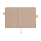 Greige Hobonichi Techo cover laid open flat on a white background, showing pink pen loops and two pale pink ribbon bookmarks.