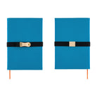 The front and back of a blue Hobonichi Techo cover shown side by side on a white background, each wrapped with a black elastic band and a natural leather pen loop.