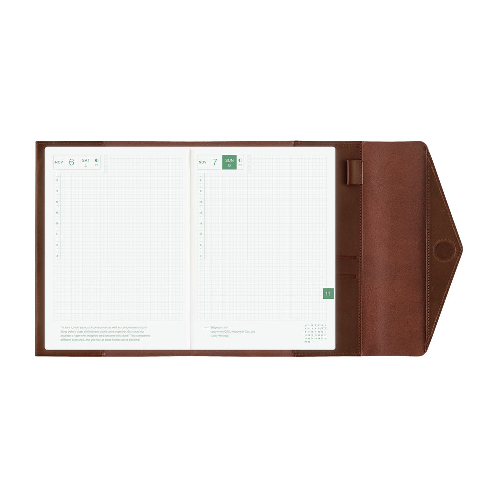 An open brown leather Hobonichi Techo cover with a white grid planner inside, shown against a plain white background.