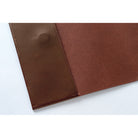 A close-up of a brown leather, showing a smooth textured panel and a stitched edge on a plain white background.