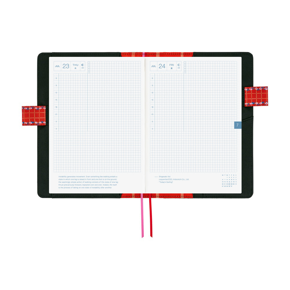 An open planner with white grid pages and a black and interior with red pen closure loops and two ribbon bookmarks hanging below, one red and one pink, on a plain white background.
