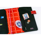 Interior details of a black Hobonichi Techo with whimsical cat illustrations. The inside cover features bright red grid fabric and black contrasting fabric, illustrative details, and several pockets.