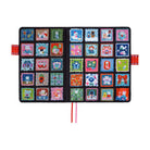 An open, flat  black Hobonichi Techo cover decorated with a colorful grid of patchwork-style square panels, each featuring different whimsical cat illustrations. It has two ribbon bookmarks, one pink and one red, and two red pen closure loops against a plain white background.