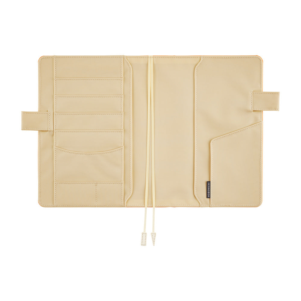 Ivory interior of a Hobonichi Techo cover laid open flat on a white background, showing multiple card and storage pockets, pen loops, and two ribbon bookmarks.