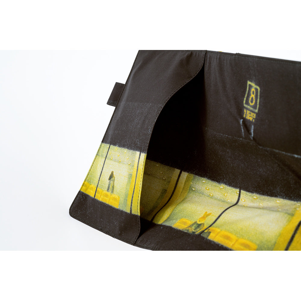 A close-up of an exterior pocket on a black fabric planner cover featuring a yellow illustrated airport scene, shown on a white background.