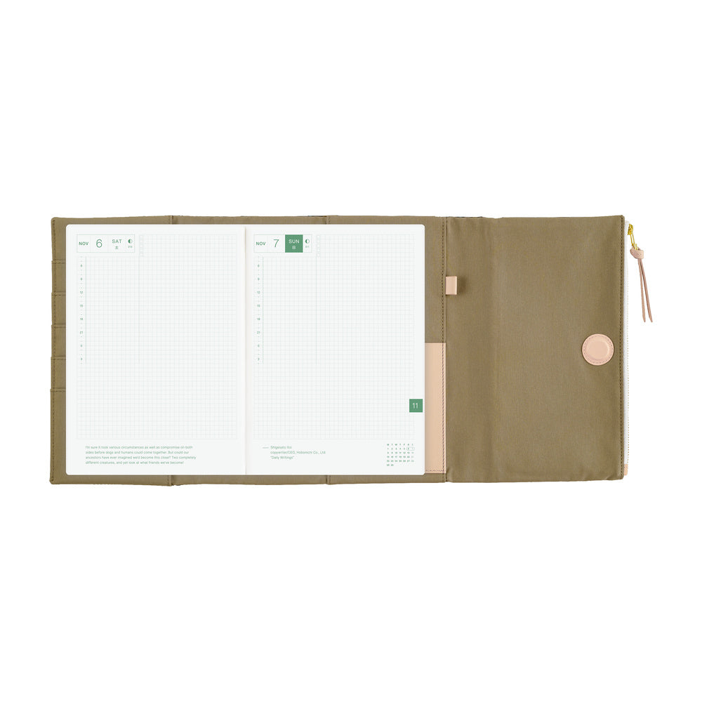 An open zippered planner in a beige fabric, showing white grid planner pages on the left and a closed flap with a magnetic closure button on the right, photographed on a plain white background.