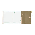 An open zippered planner in a beige fabric, showing white grid planner pages on the left and a closed flap with a magnetic closure button on the right, photographed on a plain white background.