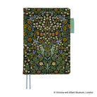 A Hobonichi Techo planner cover featuring a detailed floral and botanical pattern in green, yellow, white, and blue on a black background, with two blue ribbon bookmarks and a small turquoise tag on the right side.