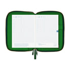 An open green-colored A5 Hobonichi zippered cover holding a gridded planner, with interior pockets, pen holder, and gold zipper visible on a plain white background.