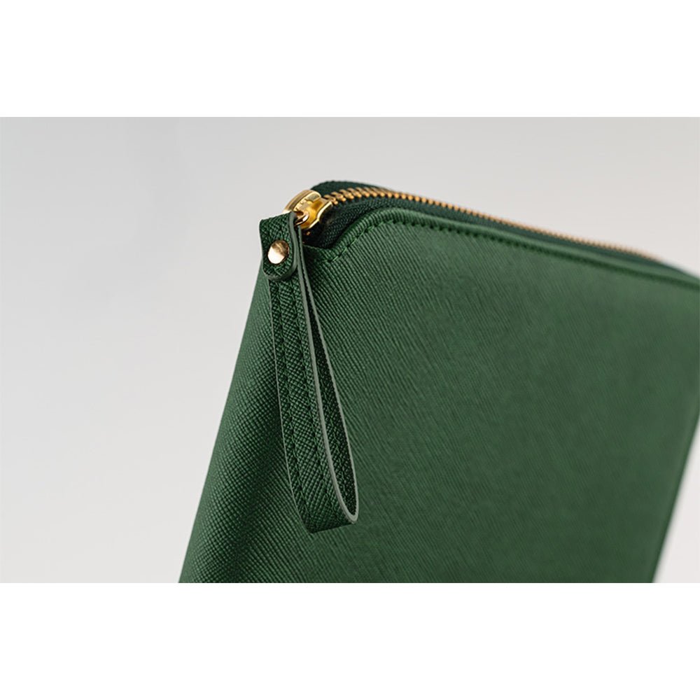Close-up of the wrist loop on a green-colored Hobonichi Techo zippered cover with gold-colored hardware on a white background.