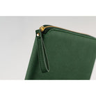 Close-up of the wrist loop on a green-colored Hobonichi Techo zippered cover with gold-colored hardware on a white background.