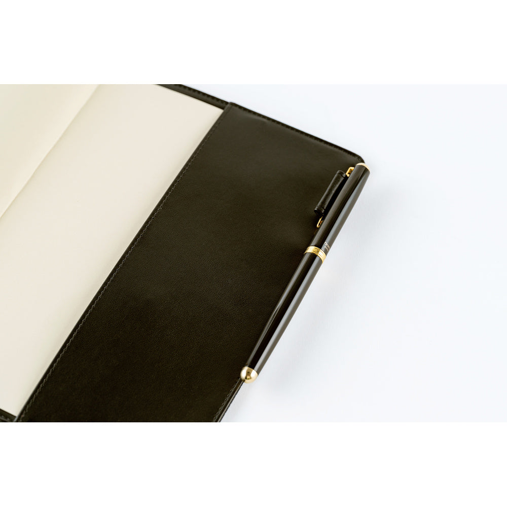 A close-up of the interior of a notebook cover with a pen loop holding a pen resting on a white surface.