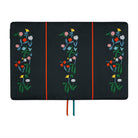 A navy fabric planner cover showing three vertical panels, each decorated with a colorful embroidered floral motif. Thin red and blue ribbon bookmarks hang from the bottom against a plain white background.