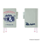 A Moomba-style planner or notebook shown from two angles on a white background. The cover is a very pale mint green with dark blue line art of Moomba and pink script text on the front, plus a small pink-and-white flower bookmark charm.