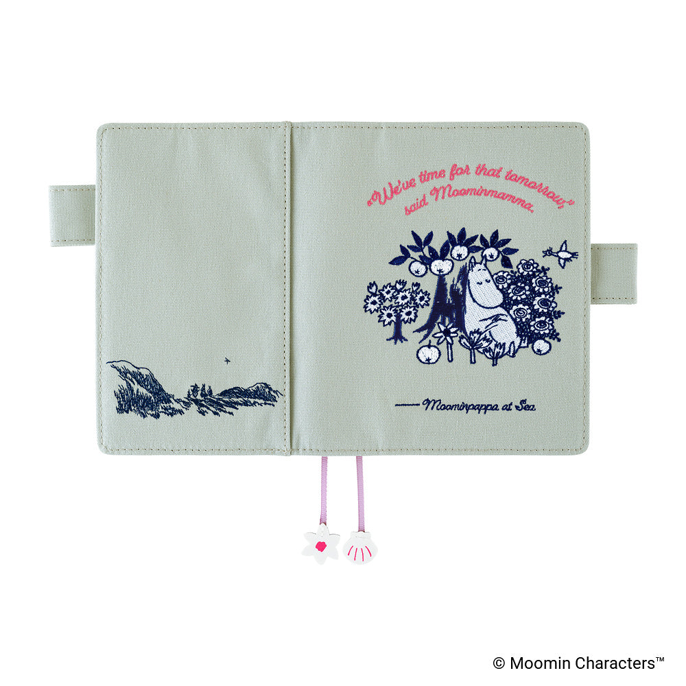 A Moombaapapa & Sea character-themed notebook or planner cover shown open against a white background. The cover is a pale sage green with navy blue illustrations of a forest scene on the left page and a character illustration with pink text on the right page.