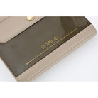 A close-up of a beige and dark brown notebook cover with gold foil text and icons, photographed on a white background.
