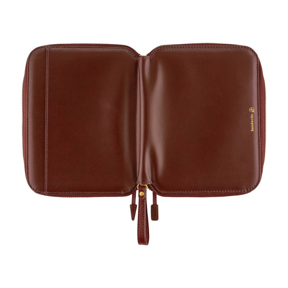 A brown leather notebook or document case shown open against a plain white background, featuring a small gold 'hobonichi' logo on the right side.