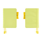 Two light yellow planner covers shown side by side on a plain white background, each with a yellow ribbon bookmark and a small yellow tab detail.