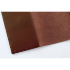 A close-up of a brown leather or faux-leather product corner showing a smooth exterior panel and a textured interior surface on a white background.