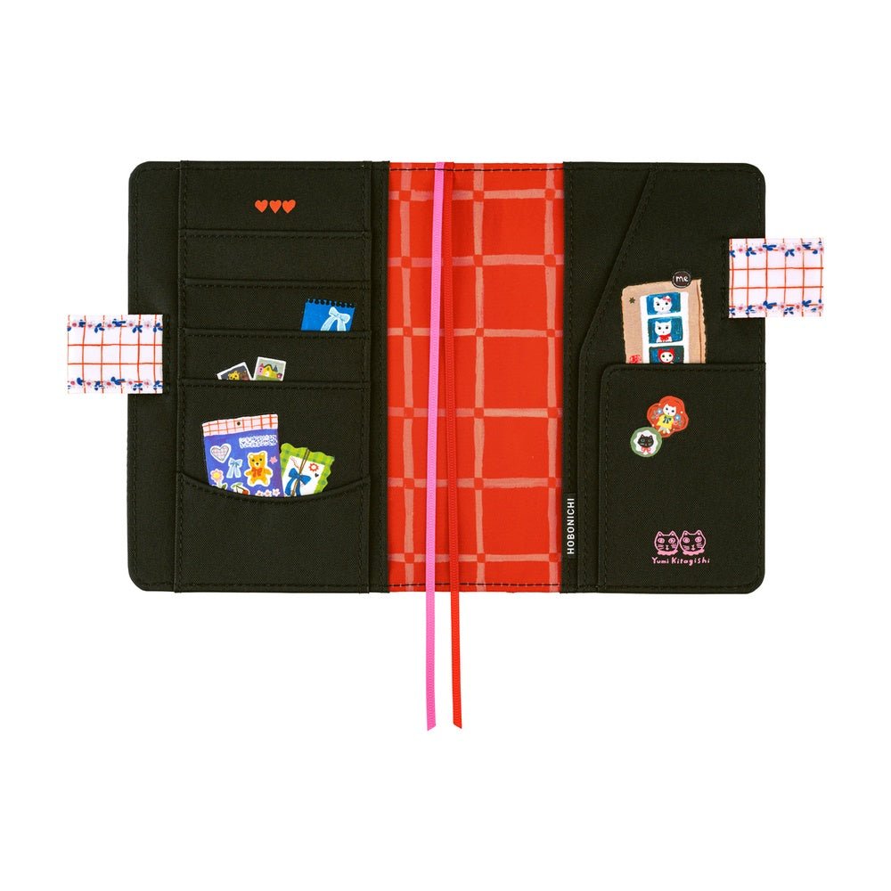 Hobonichi A6 planner cover featuring Yumi Kitagishi’s whimsical “White Cat’s Table Decorations” artwork, with a white cat-shaped teapot, teacup, colorful flowers, ribbon-tied napkin, and other cheerful tableware illustrations.