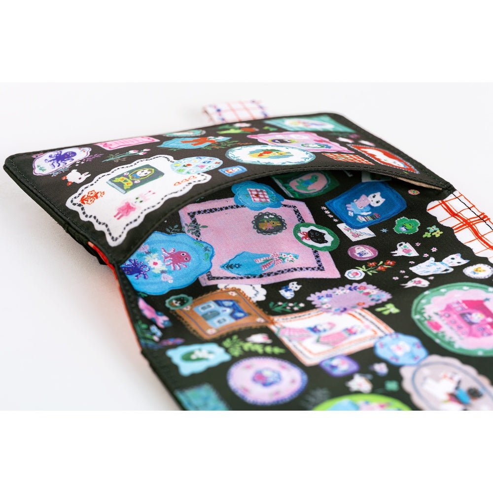 Hobonichi A6 planner cover featuring Yumi Kitagishi’s whimsical “White Cat’s Table Decorations” artwork, with a white cat-shaped teapot, teacup, colorful flowers, ribbon-tied napkin, and other cheerful tableware illustrations.