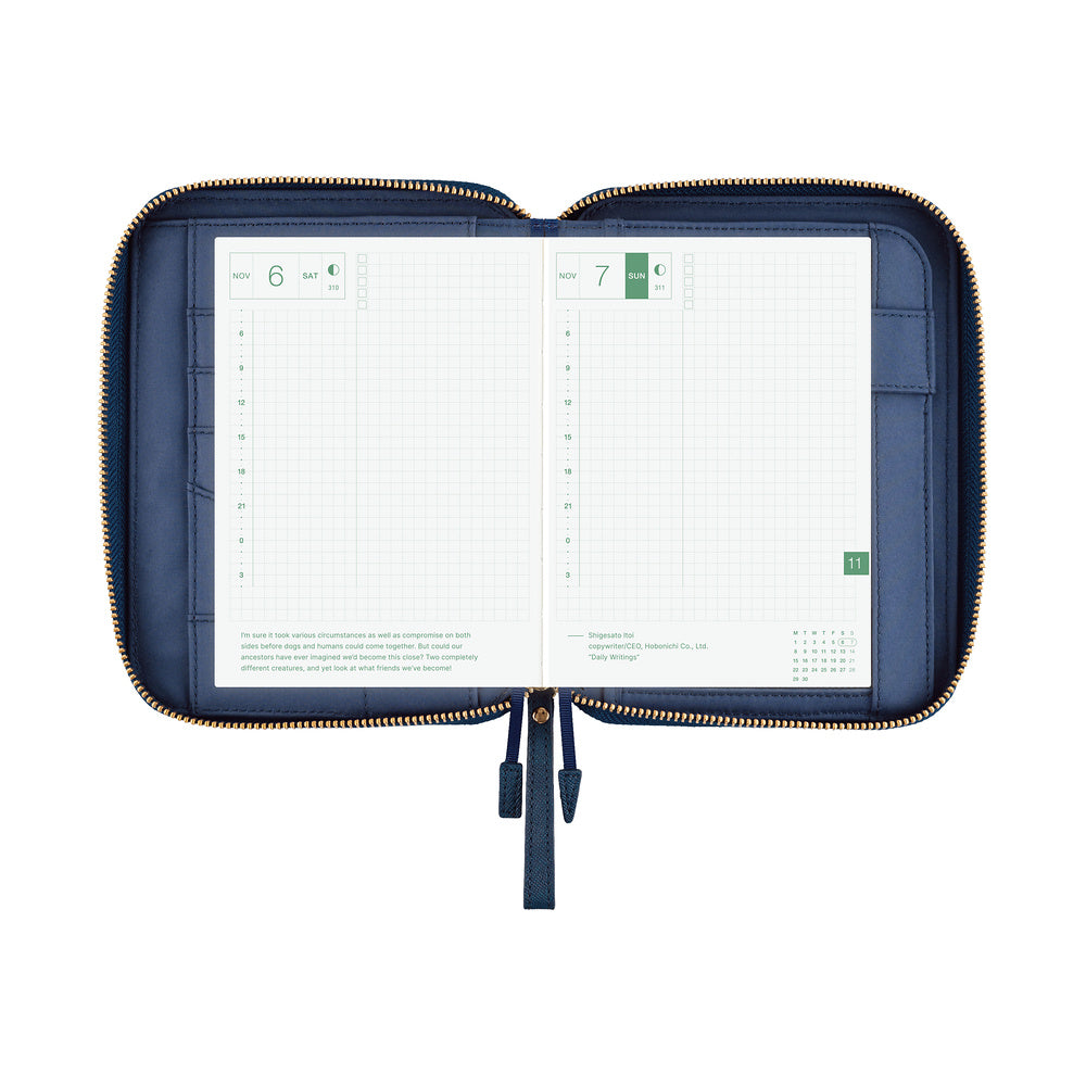 An open navy blue zippered planner case with gold-tone zipper trim, shown against a plain white background. The interior pages are white grid planner inserts.