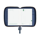 An open navy blue zippered planner case with gold-tone zipper trim, shown against a plain white background. The interior pages are white grid planner inserts.