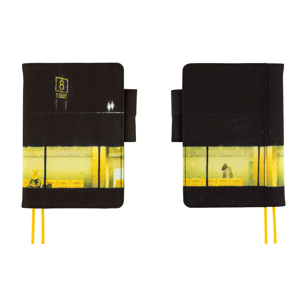 Two black hardcover notebooks with a yellow and black street scene print on the lower half, shown side by side on a white background. Each notebook has a black elastic closure tab and yellow ribbon bookmarks.