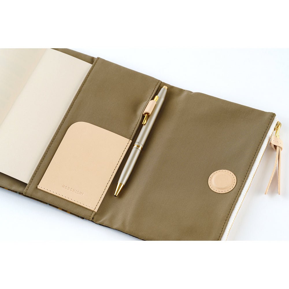 An open olive green zippered notebook or planner case with a beige interior pocket, a beige leather tab, and a metallic gold pen placed inside, shown on a white background.
