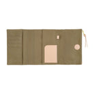 An olive green canvas organizer pouch shown open, featuring multiple card slots, a central pocket with a beige leather insert, a small beige tab, a round beige snap button, and a gold zipper pull with a beige tassel.