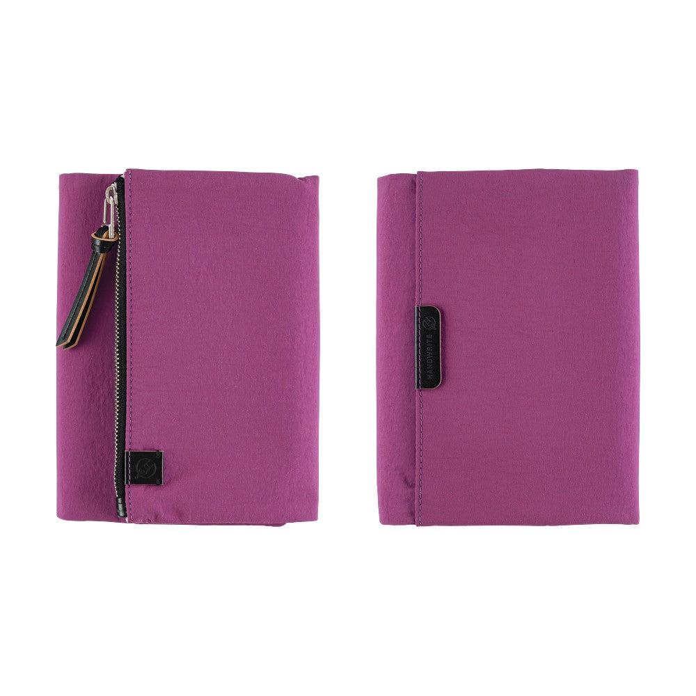 Two views of a purple zippered notebook cover on a white background, showing both the front with a zipper and pull tab, and the back with a black strap closure.