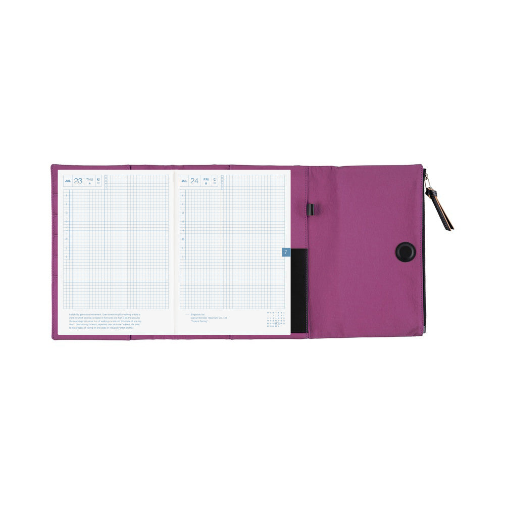 An open purple Hobonichi Tragen tri-fold cover holding a gridded planner, with interior pockets, pen holder, magnetic closure, and zippered pouch visible on a plain white background.