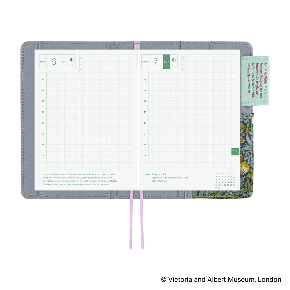 An open gray leather planner or notebook cover on a white background, showing two lined interior pages with weekly layouts, a pink ribbon bookmark, a mint sticky note, and a floral-patterned bookmark or insert.