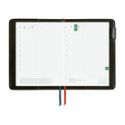 A black tablet-style planner or digital calendar display shown open on a white background, with two grid pages visible and two ribbon bookmarks in teal and red hanging from the bottom.
