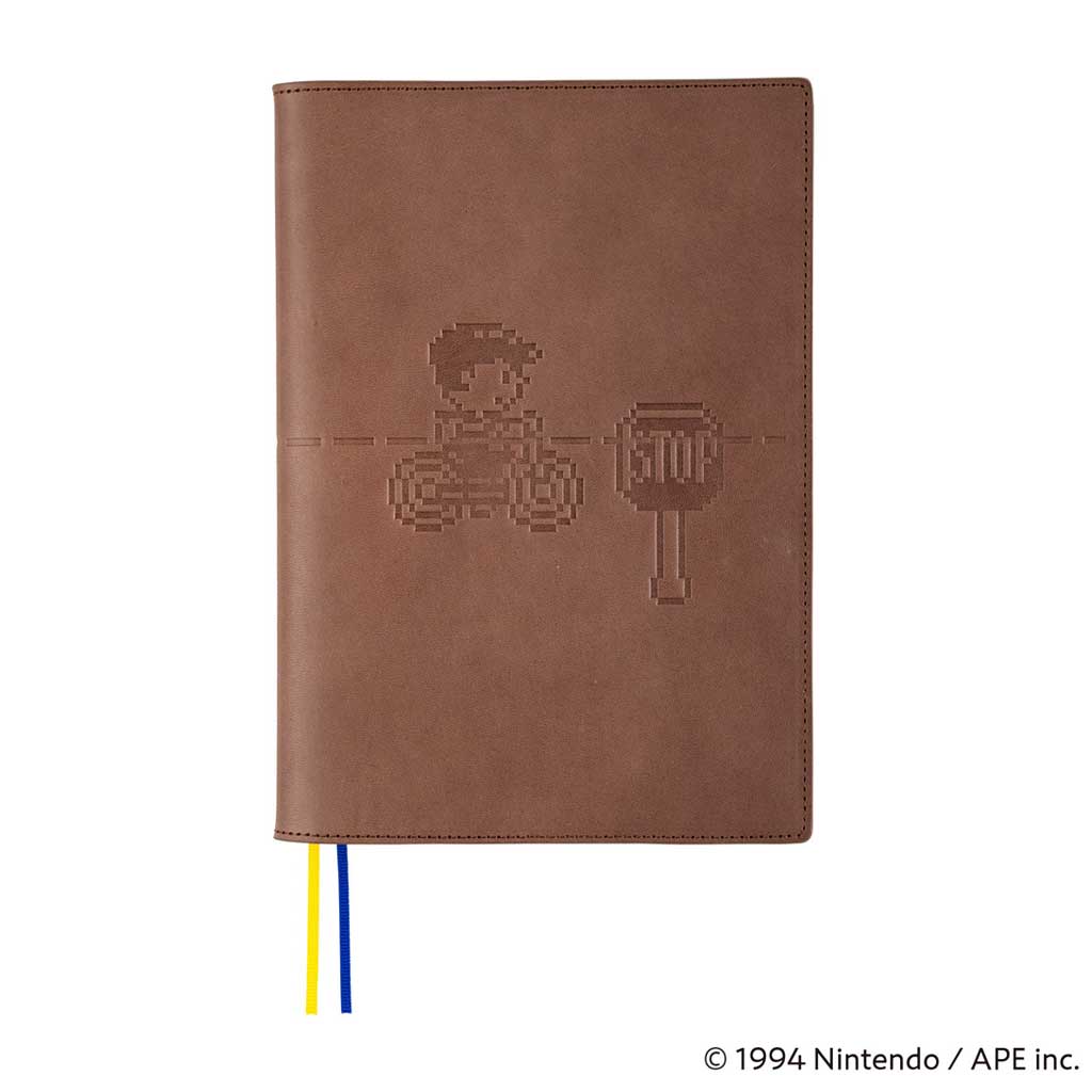 Brown leather cover with embossed MOTHER design of pixelated character on bike next to stop sign for Hobonichi Techo Cousin A5 planner on white background