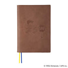 Brown leather cover with embossed MOTHER design of pixelated character on bike next to stop sign for Hobonichi Techo Cousin A5 planner on white background