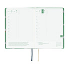 A 2027 Hobonichi HON covered in Bow & Tie fabric woven with a sheep design on a green background