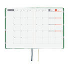 A 2027 Hobonichi HON covered in Bow & Tie fabric woven with a sheep design on a green background