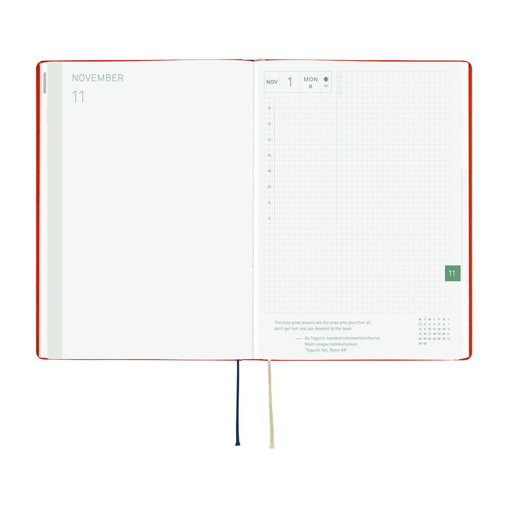 An open planner or notebook with a red cover, showing a November calendar page on the left and a grid-style weekly planner spread on the right. Two ribbon bookmarks, one cream and one navy, hang from the bottom center against a plain white background.