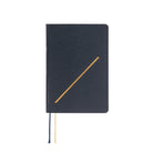 A black textured hardcover notebook with a gold diagonal line on the cover, featuring a navy blue and cream ribbon bookmark hanging from the bottom edge, set against a plain white background.