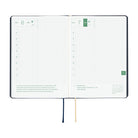 An open weekly planner spread with two white grid pages, black binding, green date headers, and ribbon bookmarks in navy and beige on a white background.
