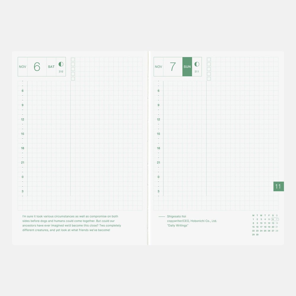 An open planner spread showing two white pages with a light green grid layout, date headers at the top, monthly calendar columns, and text near the bottom. The pages are photographed against a very light gray background.