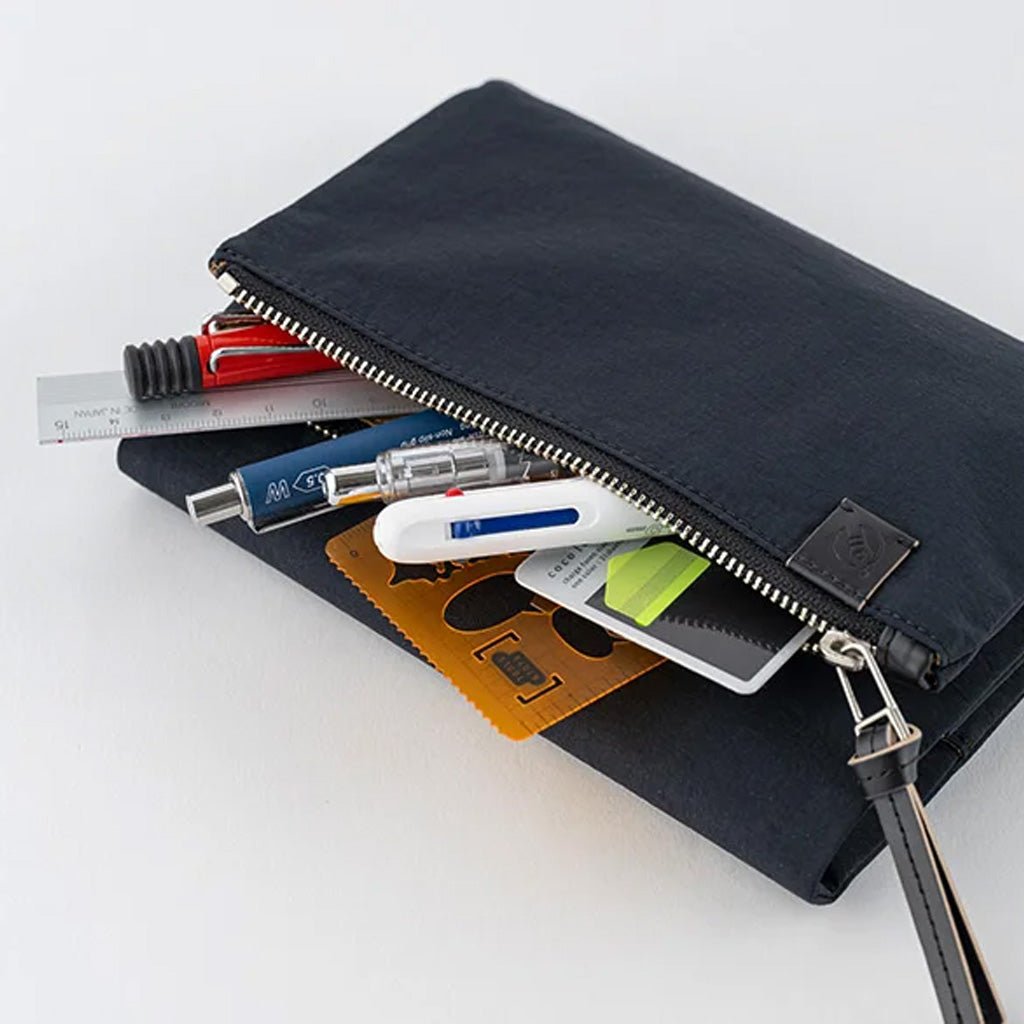A black nylon zippered pouch shown open with various stationery and utility items peeking out against a clean white background.