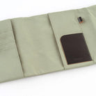 An olive green fabric organizer pouch shown open on a white background, featuring a dark brown leather card holder pocket and a small black pen hook.