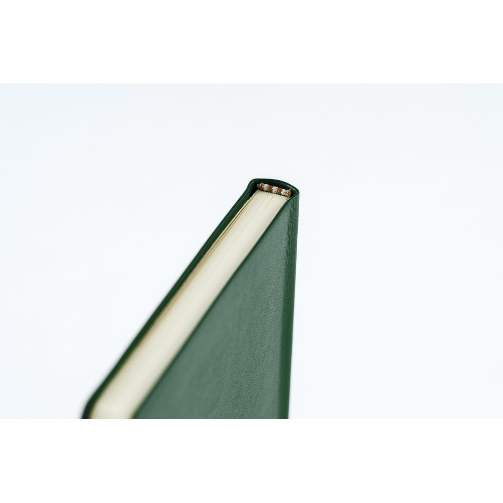 A close-up shot showing the top of a planner bound in dark green leather. 