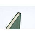 A close-up shot showing the top of a planner bound in dark green leather. 