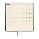 An open planner showing a two-page monthly calendar on cream pages. 